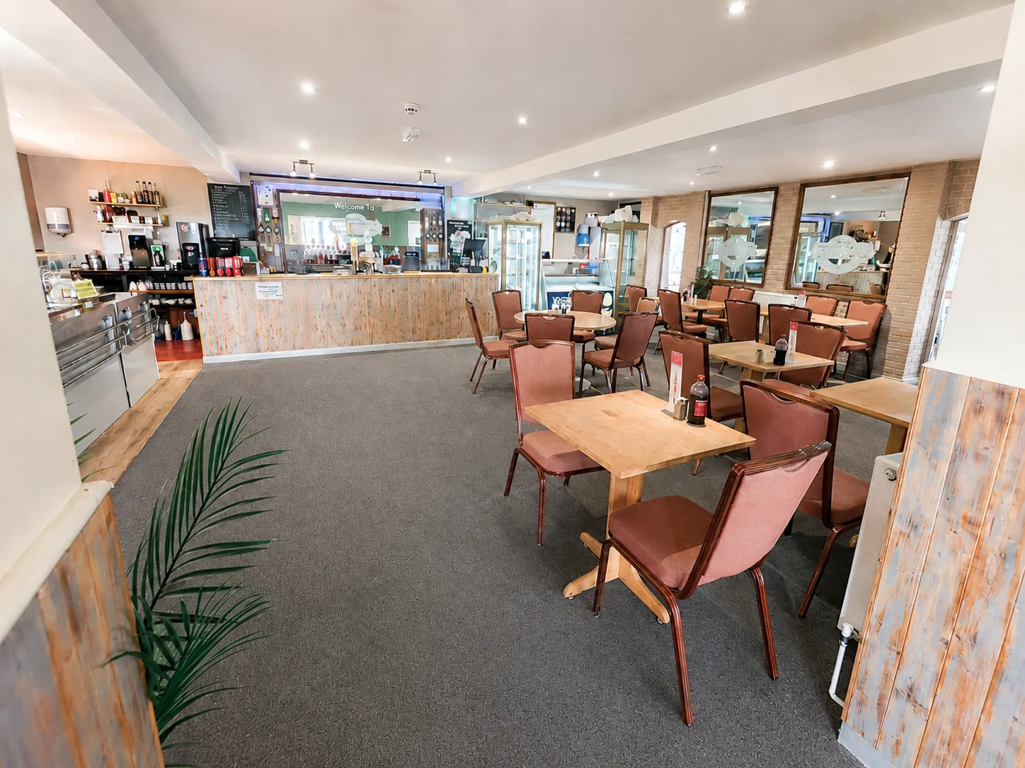 Inside The Windy Ridge — wooden serving counter, dining tables and maroon chairs in the family-run eating house