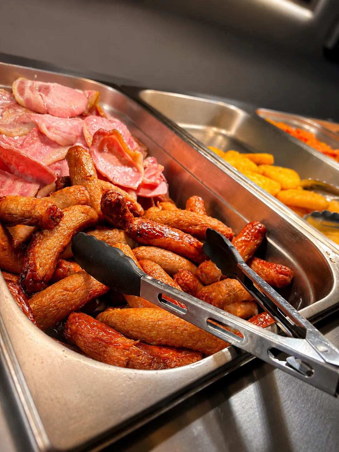 Close-up of golden sausages and crispy bacon on the breakfast buffet counter at The Windy Ridge